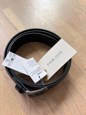Svart bälte från Pier One - Stilrent svart bälte från Pier One i slät design med ett metallspänne. Helt nytt och oanvänt