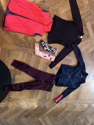 Ridkläder!🤗 - Säljer ett komplett träningsset med vinröda tights S 130, svart långärmad tröja S 146/152, marinblå sportjacka med röda detaljer S 133/142, rosa quiltad väst S 133/142 samt två par sportiga strumpor i rosa och blått med mönster S 35-38. Perfekt för barn som rider! 