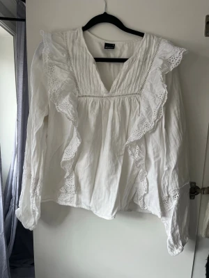 Vit blus med volanger - Säljer en vit blus med långa ärmar och v-ring. 