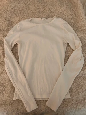 Vit långärmad topp - En enkel och stilren vit långärmad topp med rund halsringning. Tillverkad i mjuk bomull som känns skön mot huden. Perfekt att matcha med jeans eller kjol för en clean look.