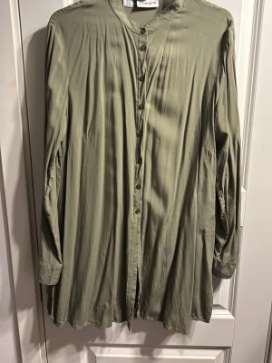 Ljusgrön lång skjorta med knappar - Säljer en ljusgrön långärmad skjorta med knappar hela vägen framtill och avslappnad passform. Skjortan har en mjuk, slät yta och faller snyggt. Perfekt för dig som gillar en loose och chill stil.