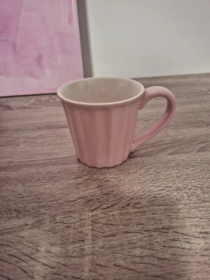 Rosa räfflad kaffekopp - Söt kaffekopp i keramik med räfflad utsida och mjukt rundat handtag. Koppen är ljusrosa på utsidan och vit på insidan, perfekt för te eller kaffe. Enkel men stilren design som passar i de flesta kök.