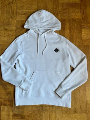 Vit hoodie från J.Lindeberg - Snygg vit hoodie från J.Lindeberg i storlek M med klassiska märket på bröstet. Tröjan är i riktigt bra skick.