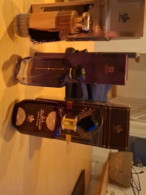 Lyxiga orientaliska parfymer - Tre exklusiva parfymer i eleganta flaskor med orientaliska detaljer. Flaskorna är i lila, guld och transparent glas med dekorativa lock och mönster. Perfekt för dig som gillar unika dofter och snygg design på parfymhyllan.