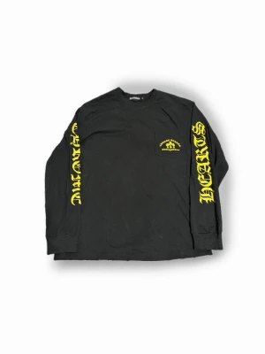 Svart långärmad t shirt Chrome Hearts - Svart långärmad t shirt från Chrome Hearts med gul text och tryck på både ärmar, bröst och rygg. Storlek M sitter som en M!