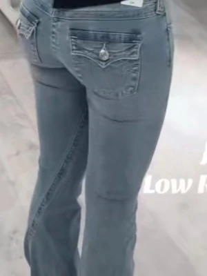 Joey ljusblå low rise flare jeans - Ljusblå jeans med låg midja och utsvängda ben, modellen Joey. Snygga detaljer på bakfickorna med knappar och broderier. Perfekt för dig som gillar en trendig och avslappnad look. Materialet är klassisk denim. Skriv privat för egna bilder, köptes för 1300