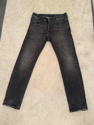Svarta tapered jeans från Jack & Jones - Säljer ett par svarta tapered jeans från Jack & Jones. Jeansen har en snygg tvättad look, klassisk femficksmodell och smalare ben. Perfekta för dig som gillar en avslappnad men ändå stilren stil.
