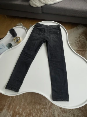 Svarta slim-fit jeans från Dondup - Säljer ett par svarta slim-fit jeans från Dondup med schyssta slutningar och med klassisk femficksmodell och diskret logga på bakfickan. Jeansen har en smal passform och är tillverkade i ett mjukt denimtyg som sitter snyggt. Perfekta för dig som gillar en stilren look. Storlek 13år. Nypris 2200kr