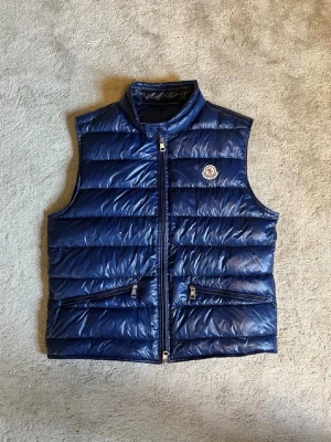 Moncler Gui väst - Tja. Säljer nu denna sjukt snygga och eftertraktade Moncler västen i den populära modellen Gui. Den är i jättefint skick och nästan som ny. Storlek 2 vilket motsvarar S/M(liten i storleken). Jättefin blå färg. Köpt på Haiendo för 3800kr och KVITTO finns. Nyrpris ligger runt 9000kr. De grå Dondup jeansen i min profil skickas med vid köp🔥🔥. Hör av er vid frågor/bilder eller funderingar.