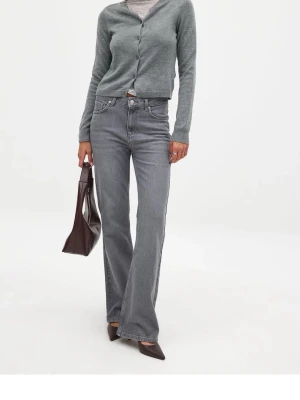 Grå bootcut jeans med hög midja - Säljer ett par snygga grå jeans med bootcut passform och hög midja. Jeansen har klassiska fem fickor, bälteshällor och stängs med dragkedja och knapp. Tillverkade i ett mjukt denimtyg som ger en skön känsla och stilren look. Helt nya med prislapp kvar!