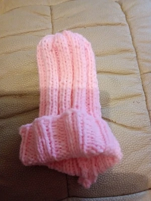 Rosa ribbstickad mössa baby 0-5 månader - Söt rosa baby  ribbstickad mössa med uppvikt kant. Mössan är handstickad i mjukt garn och har en enkel, klassisk form som passar perfekt till kalla dagar. Den ljusrosa färgen ger en gullig och trendig look. 100% polyester. Mjuk och varm tjock.