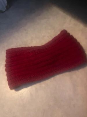 Vinrött stickat pannband - Mysigt vinrött stickat pannband i ribbad design. Pannbandet har en twist framtill som ger en snygg detalj och är gjort i mjukt garn, perfekt för att hålla håret på plats och värma öronen under kyliga dagar.