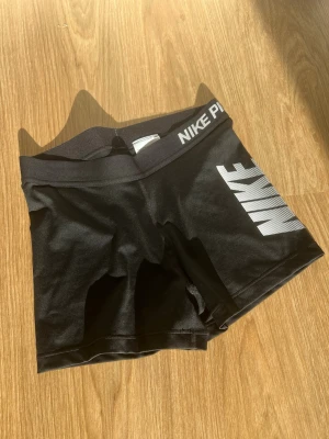 Svarta Nike Pro träningsshorts - Säljer ett par svart/vita träningsshorts från Nike Pro. Storlek M men skulle säga att de är mer som S. Fråga gärna om du vill ha fler bilder :)   Säljanledning: Kommer ej till användning.  Passform: Tight.  Material: Polyester, elastan.