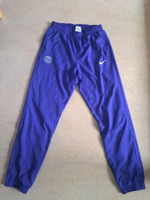 PSG Nike träningsbyxor - Snygga träningsbyxor från Nike. Köpta från Unisports hemsida. Säljs så billig då den har en liten repa på ena knäet enligt bild. Har även en matchande jacka som säljs separat.