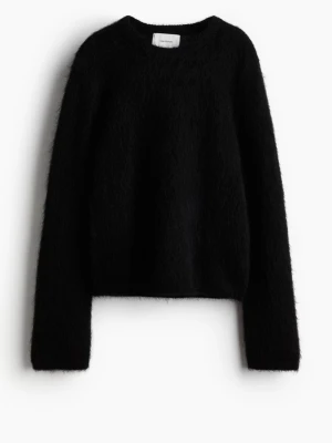 Svart fluffig stickad tröja - Mysig svart stickad tröja med fluffig yta och rund hals. Tröjan har långa ärmar och en enkel, rak passform som passar perfekt till jeans eller kjol. Materialet ser ut att vara en mjuk mix, troligen med mohair eller liknande för extra fluff.