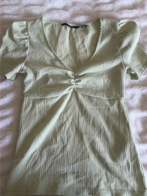 Ljusgrön topp från vero moda - Säljer nu en ljusgrön topp med puffärmar och v-ringning. Toppen kan kombineras med kjol eller jeans. Perfekt under sommaren då man är lite brun!