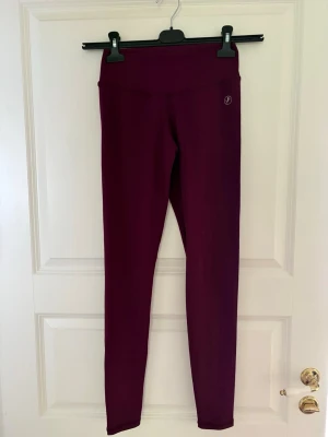 Vinröda leggings med hög midja - Snygga vinröda leggings med hög midja och stretchigt material. Diskret logga på höften. Perfekta för en chill och sportig look. Tight passform och mjukt tyg som sitter skönt hela dagen. Kolla gärna mina andra annonser❗️