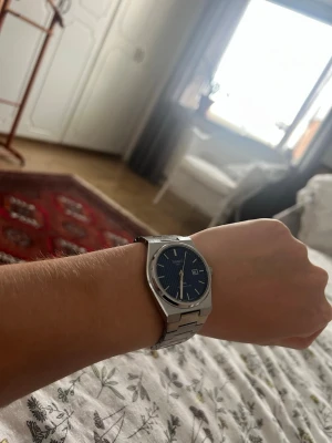 Tissot PRX klocka med blå urtavla - Snygg Tissot PRX klocka i rostfritt stål med blå urtavla och datumvisning. Klockan har ett klassiskt armband i silverfärgat stål och stilrena indexmarkeringar. Perfekt accessoar för dig som gillar tidlös design och kvalitet.