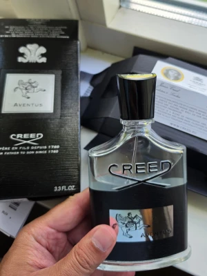 Creed Aventus Eau de Parfum 100ml - Creed Aventus är en exklusiv parfym i en elegant, genomskinlig glasflaska med svart och silverdetaljer. Flaskan rymmer 100 ml och har en stilren svart kork. Doften är ikonisk och passar dig som vill sticka ut med en lyxig och tidlös parfym. Obs Använt ca 20% av innehållet. Dvs 80 ml kvar. 
