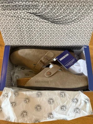 Taupe mocka Birkenstock Boston - Snygga Birkenstock Boston sandaler i beige mocka med justerbart spänne och klassisk korksula. Perfekta för en chill och stilren look. Modellen har täckt tå och är superbekväm för vardagsbruk. Ikonisk design som funkar året runt. ‼️skickar inom 24H‼️ *PRIS GÅR ATT DISKUTERAS**