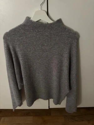 Grå stickad tröja med hög krage - Mysig grå stickad tröja med hög ribbad krage och långa ärmar. Storlek S men lite större i Storlek. Använde fåtal gånger 
