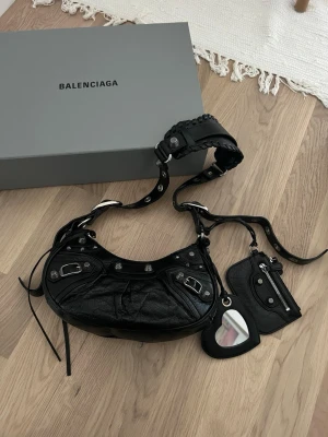 Balenciaga le cagole xs shoulder bag - Knappt använd. Har dock ett litet märke på baksidan, se bild 2. Kvitto finns. Nypris: 1 990€ (21 989,14kr). Kuvertet på den sista bilden är det enda som inte ingår då returettikett med min adress är där.