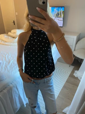 Svart prickig halterneck topp💞 - Säljer en svart halterneck topp med vita prickar. Toppen är ärmlös och har öppen rygg. Den är ifrån hm och är i storlek xs💓