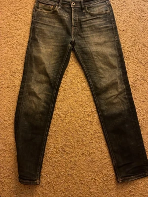 Mörkblå Jack & Jones slim jeans  - Säljer ett par mörkblå slim fit jeans med en klassisk femficksdesign. Jeansen är tillverkade i ett mjukt bomullsmaterial med lite stretch för extra komfort.
