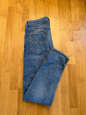 Blå raka jeans med bakfickor - Säljer ett par klassiska blå jeans i rak modell. Jeansen har två bakfickor med dekorativa sömmar och normal midja. Materialet är mjukt och slitstarkt denim. Perfekta till vardags och passar till det mesta. Skickas nytvättade! Storlek 33-34