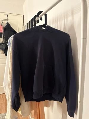 Mörkblå hoodie  - En enkel och stilren mörkblå hoodie med klassisk magficka och huva. Hoodien har ribbade muddar vid ärmslut och nederkant. Storlek Xxs men passar även XS/liten S beroende på hur man vill att den ska sitta. 