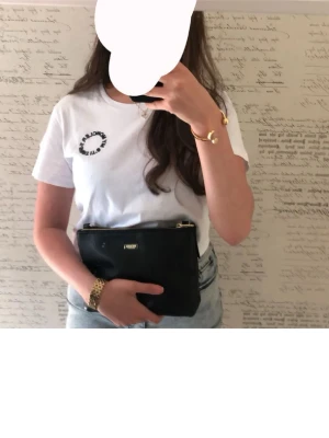 Vit t-shirt med tryck - Säljer en fräsch vit t-shirt med svart texttryck vid bröstet. T-shirten har rund halsringning och korta ärmar. Perfekt till jeans eller shorts för en clean och enkel look. Moncler 