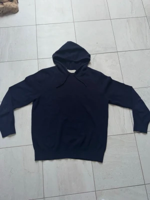 Sayless cashmire hoodie  - En enkel och stilren mörkblå hoodie med huva och dragsnören. Hoodien har lång ärm och rak passform, perfekt för en avslappnad look. Tillverkad i mjukt material som känns skönt mot huden.