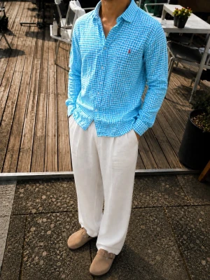 Polo Ralph Lauren Skjorta – Blå/Vit Gingham Check 100% Bomull - Snygg Polo Ralph Lauren skjorta i en stilren blå och vit gingham-rutig design. Skjortan har den klassiska broderade Polo Ralph Lauren-loggan på bröstet och är tillverkad i 100 % bomull.  Perfekt för en stilren och avslappnad sommarlook, exempelvis tillsammans med linnebyxor, jeans eller shorts.  • Polo Ralph Lauren • Blå/vit gingham-rutig • 100 % bomull • Broderad Polo-logga • Långärmad • Klassisk button-down-krage • Made in Indonesia 