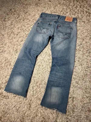 Levis 512 bootcut jeans  - Säljer ett par blå Levis 512 bootcut. Jeansen har två bakfickor och klassisk femficksdesign. Materialet är denim i bomull och de har en tvättad, något sliten look. Storlek 30/30 