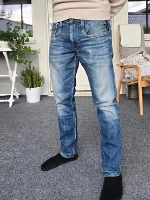 Blå Replay grover jeans  - Säljer ett par blå jeans med rak passform och normal midja. Jeansen har fem fickor, dragkedjegylf och subtila slitningar för en avslappnad look. Perfekta till vardags och passar till det mesta. Materialet är troligtvis bomull med lite stretch.