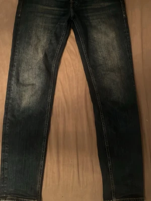 Mörkblå raka jeans från Jack & Jones - Säljer ett par mörkblå jeans med raka ben och lätt slitna detaljer framtill. Jeansen har klassisk femficksdesign och kontrastsömmar. Perfekta för en avslappnad och stilren look. Materialet är troligtvis bomullsdenim.