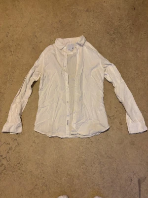 Vit linne skjorta - Säljer en vit klassisk linne skjorta med lång ärm och knappar framtill. Skjortan har en enkel krage och är tillverkad i ett mjukt bomullstyg. Perfekt till både jeans och kostymbyxor. Pris kan diskuteras