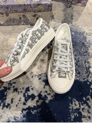 Christian Dior gråvita sneakers - Snygga sneakers från Christian Dior i grått och vitt med ikoniskt Dior. Mycket fint skick. Har tyvärr inget äkthetsbevis.