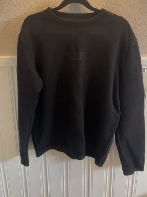 Svart sweatshirt från EA7 Emporio Armani - Säljer en svart sweatshirt från EA7 Emporio Armani. Tröjan har rund halsringning, långa ärmar och diskret logga på bröstet. Tillverkad i mjukt material som känns skönt mot huden. Perfekt för en clean och stilren look.