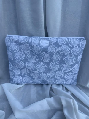 Datorfodral Seashells  - Laptopfodral i rejält tyg med snäckmönster. Vit och blå med beige innertyg och vit matchande dragkedja. Rymmer laptop och sladd eller anteckningsbok. Passar laptop med maxmått 32x24cm.