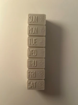 Praktisk dosett  - Praktisk dosett i plast med sju fack, ett för varje veckodag. Locken är märkta med veckodagar på engelska och punktskrift. Har aldrig kommit till användning. 
