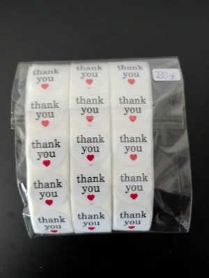 Thank you-klistermärken med hjärta 230 st - Ett paket med runda vita klistermärken med texten 'thank you' och ett rött hjärta under. Perfekta för paket, brev eller presenter. Förpackningen innehåller flera rullar med totalt 230 stycken etiketter.
