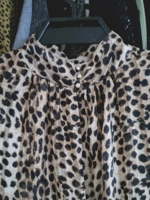 Ny Leopardmönstrad blus med pärlknappar str S - Ny aldrig använd 🌸Snygg blus med leopardmönster i beige, svart och brunt. Hög krage och dekorativa silverfärgade pärlknappar framtill. Tunt, lätt material som ger ett luftigt intryck. Perfekt för dig som vill sticka ut med ett djurmönster.🌸str S 