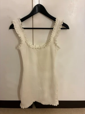 Vit kort klänning med pärlor - Vit mini klänning från zara. Jätte söt med prälor och volanger , kommer inte till nån använding längre.