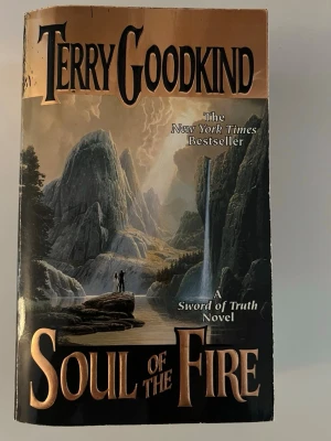 Soul of the Fire av Terry Goodkind - Fantasyroman på engelska med hård pärm, skriven av Terry Goodkind. Boken är en del av Sword of Truth-serien och har ett omslag med dramatiskt bergslandskap, vattenfall och två personer. Perfekt för dig som gillar episka äventyr och magi.