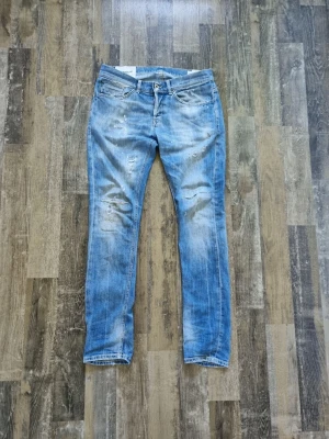 Dondup jeans  - Säljer ett par blå slim jeans från dondup med slitningar och tvättade detaljer. Jeansen har klassisk femficksmodell, låg midja och dragkedjegylf. Perfekta för en avslappnad och trendig look.