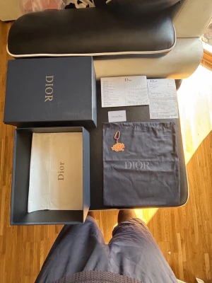 Dior B30 Box 41 Dustbag Kvitto 10,000 HKD + Syna World Charm - Komplett paket - Dior box 41 med lock, silkespapper, dustbag, kort, booklet, garanti-kort och kvitto från Hong Kong 10,000 HKD ca 12,300 SEK + Syna World keychain roseguld. Rensar rummet och behöver ej kvar, säljer för extra pengar. Inga skor ingår.