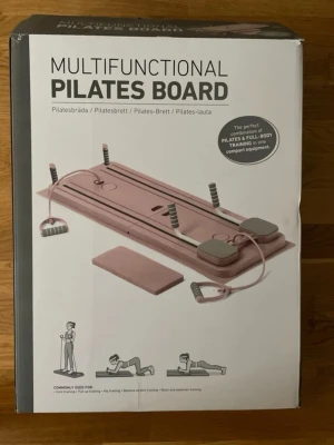 Multifunktionell pilatesbräda rosa - Säljer en multifunktionell pilatesbräda i rosa med handtag och motståndsband. Perfekt för helkroppsträning, core, balans och styrka. Kompakt design som är enkel att förvara och ta med. Passar både hemma och på gymmet.