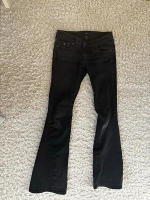 Svarta bootcut jeans från true religion  - Säljer ett par svarta bootcut jeans från true religion med klassisk femficksmodell och normalhög midja. Jeansen har utsvängda ben och är tillverkade i stretchigt denimtyg för skön passform. Perfekta till sneakers eller boots.