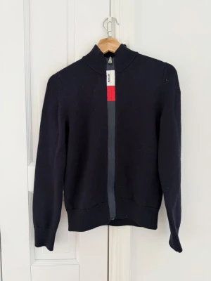Mörkblå stickad ziptröja Moncler - Sjukt Snygg mörkblå stickad ziptröja från Moncler använd fåtal gånger mycket bra skick hör av dig ifall du vill har fler bilder så skickar jag fler. Dragkedjan har en cool detalj med röd och vit rand samt Moncler-logga. Passar snyggt till ett par jeans eller liknade eller linnebyxor/shorts pris kan diskuteras vid snabb affär💨🤩